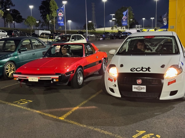 Fiat X1/9 with a Dallara wide-body kit jacked up in the pits for inspection